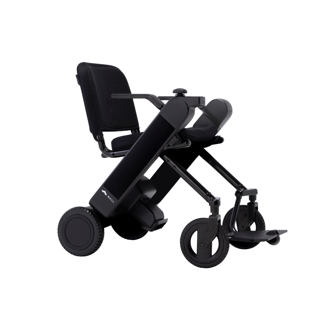 The Whill Model F Lightweight Portable Electric Wheelchair, featuring large rear wheels, smaller front wheels, a mesh seat and backrest, and a foldable footrest in sleek black is shown. Specifications and warranty info available on request.